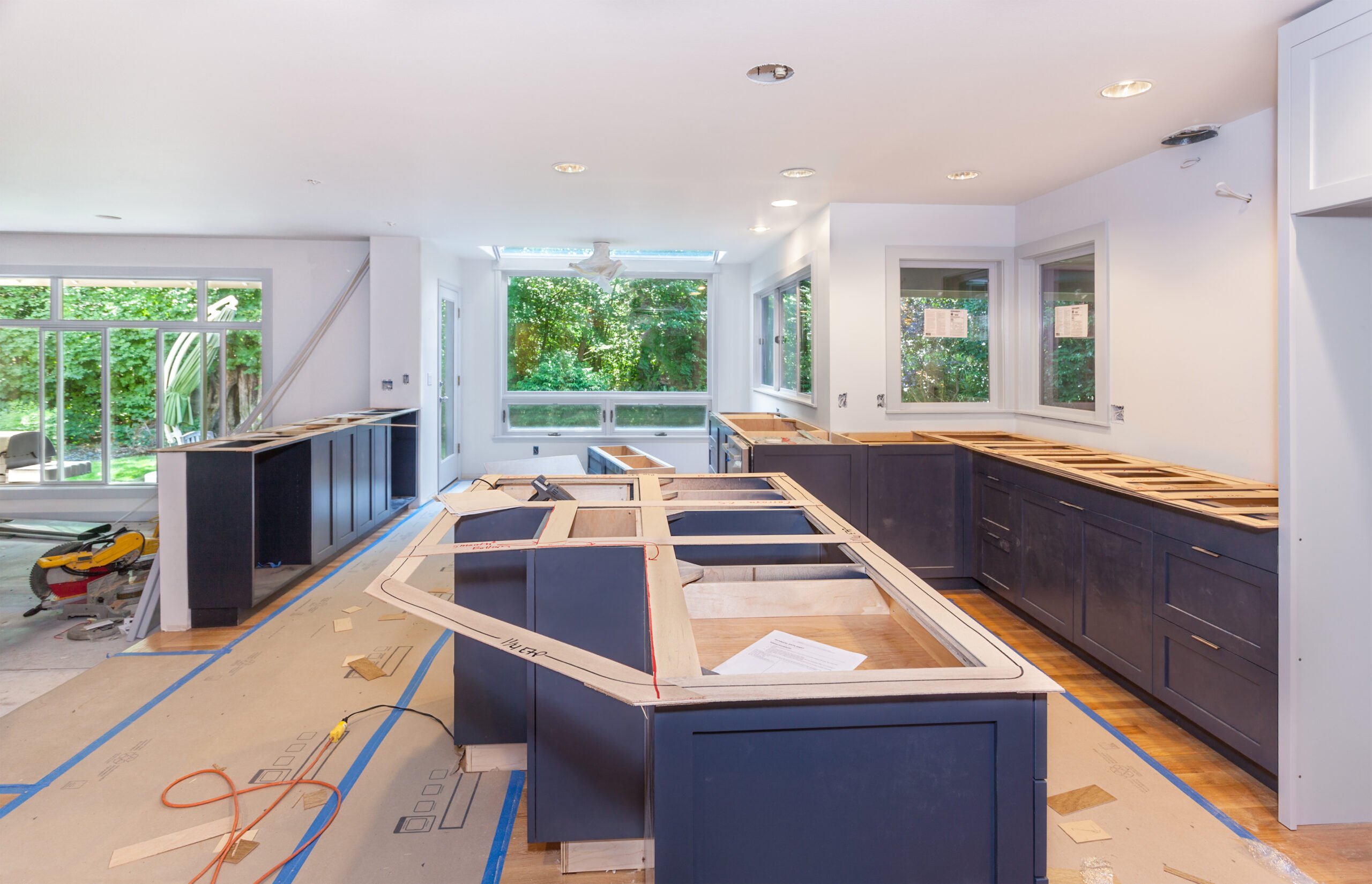 Unfinished kitchen with navy blue cabinets and island without countertops, under construction.